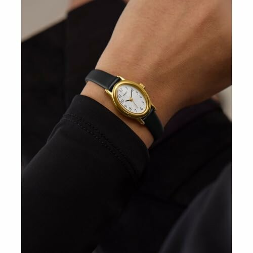 Elegant gold wristwatch with black leather strap on wrist