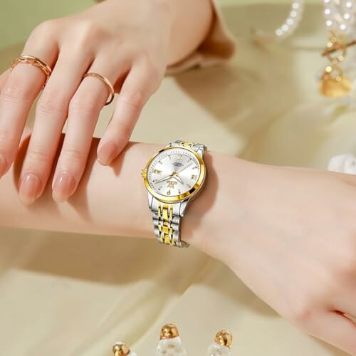 Elegant wristwatch with a gold and silver band on a person's wrist.