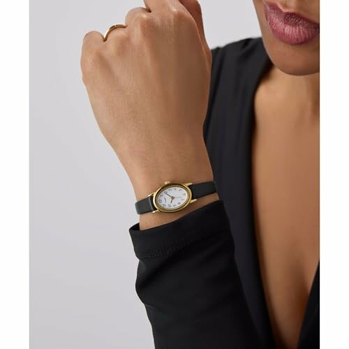 Woman wearing an elegant wristwatch with a black strap. 
