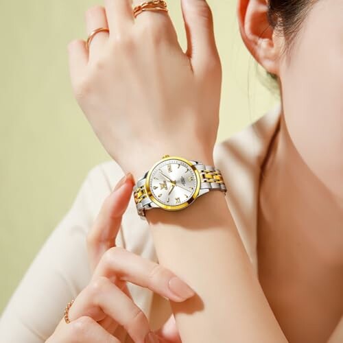 Person wearing a stylish wristwatch with gold and silver bands.
