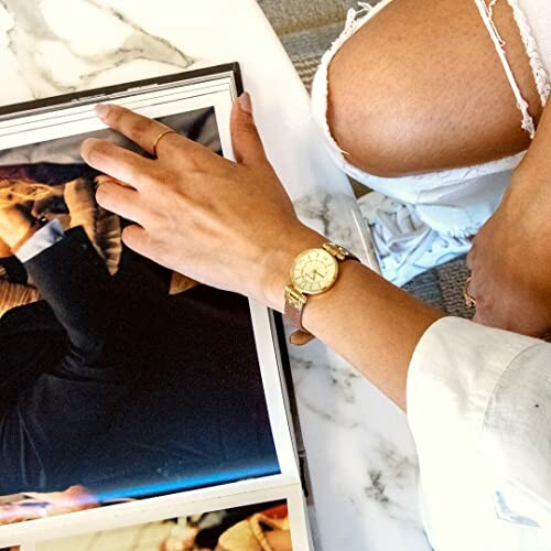 Person wearing a gold watch browsing a photo book.