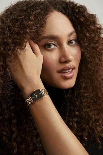 Woman with curly hair wearing a gold watch.